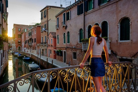 Young woman leaning against a bridge on the Rio Santa Catherina in the evening light