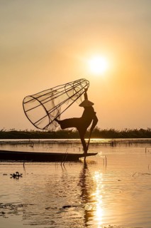 Fisherman at Inle Lake with traditional Intha conical net at sunset