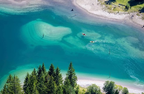 People on a stand-up paddle and kayak on the shore of Plansee