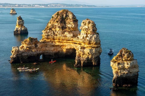 Kayakers paddling around rock formations in the sea
