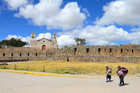 Indigenous woman in front of the Inca sun temple with colonial cathedral on top
