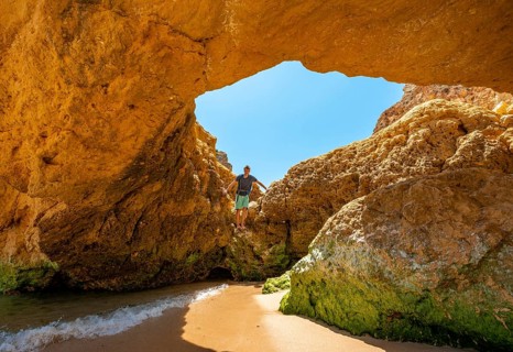 Young man standing in a rock cave with hole
