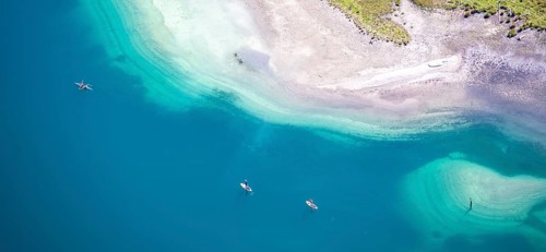 People on a stand-up paddle and kayak on the shore of Plansee