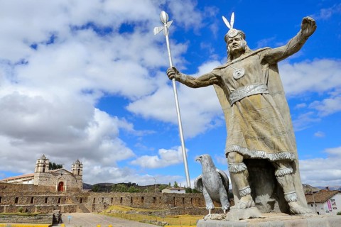 Statue of the Inca Pachacutec in front of sun temple with attached cathedral from the colonial period
