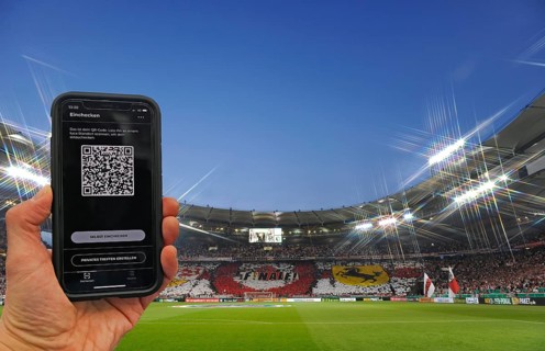 Hand holds smartphone with Luca app for digital contact tracking in packed football stadium