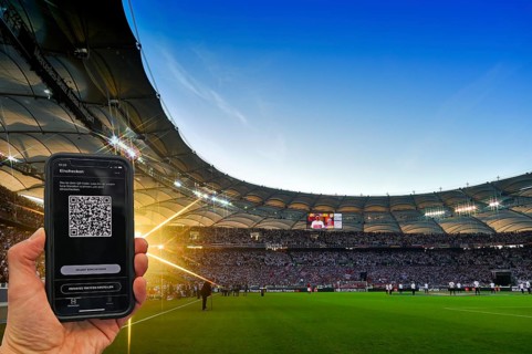 Hand holds smartphone with Luca app for digital contact tracking in packed football stadium