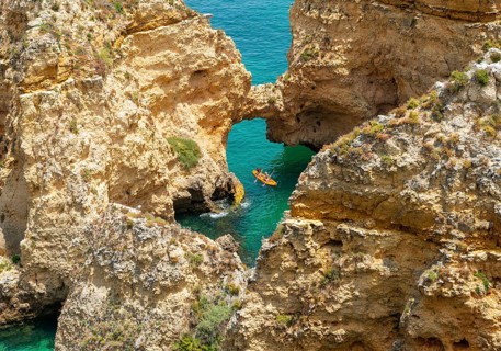 Kayak in the turquoise sea driving through rock arches