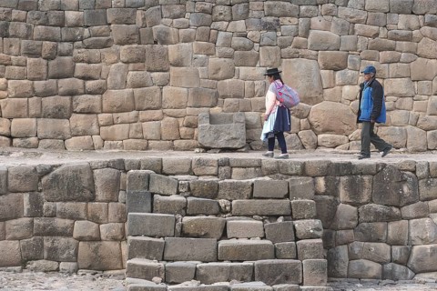 Old indigenous couple walking on the ruins of the Inca Temple of the Sun