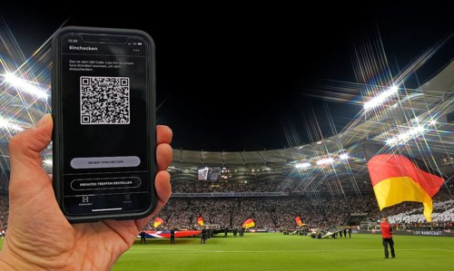 Hand holds smartphone with Luca app for digital contact tracking in packed football stadium