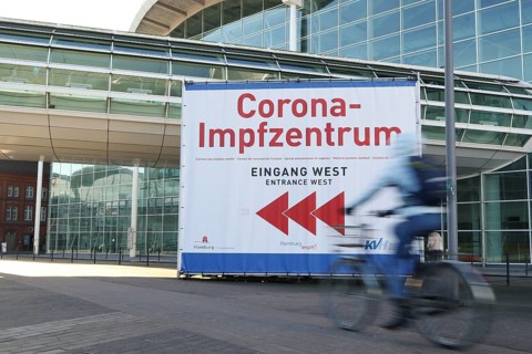Bicyclist in front of Corona-Impfzentrum Hamburg in the exhibition halls