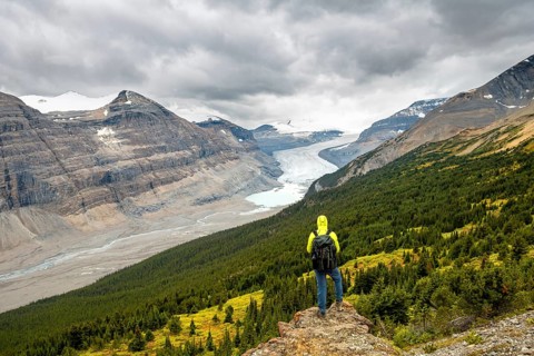 Hiker standing on rocks overlooking valley with glacier tongue