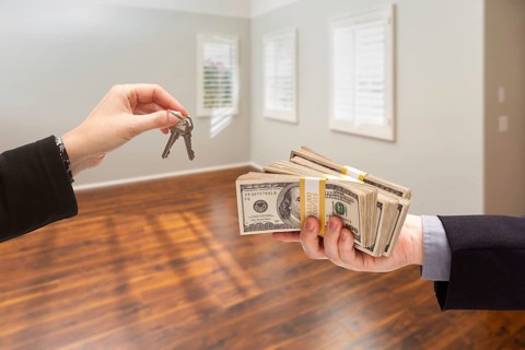 Real estate agent hands over new house keys for cash inside empty room