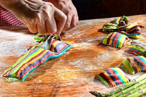Cook cutting out fresh colorful ravioli with ravioli cutter