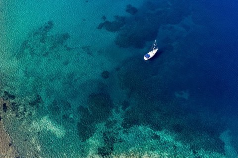 Aerial of a sailing boat in the clear waters of Limnionas beach