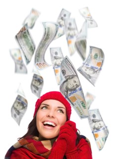 Young excited warmly dressed woman with $100 bills falling money around her on white