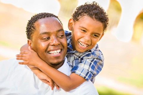 Happy african american father and mixed race son playing at the park