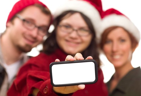 Girl with friends and santa hats holding blank white smart phone