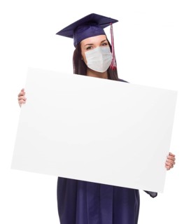 Graduating female wearing medical face mask and cap and gown holding blank poster board isolated on a white background