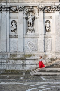 Young woman with red dress in front of white church