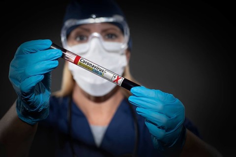 Female Lab Worker Holds Test Tube of Blood Labeled Coronavirus COVID-19 Disease