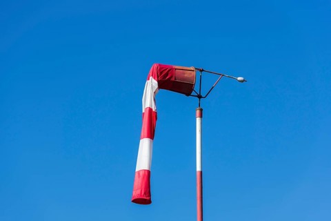 Red and white windsock against blue sky