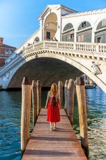 Young woman with red dress at a pier with boats