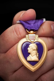 Male hand holding the United States armed forces purple heart medal