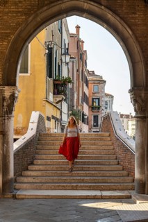 Young woman with red skirt walks through archway