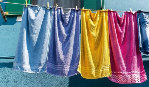 Colorful laundry on clothesline in front of blue house wall