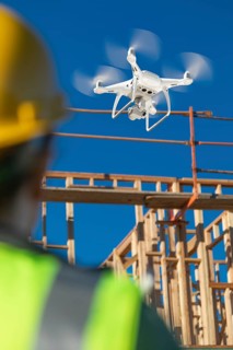 Female pilot flies drone quadcopter inspecting construction site