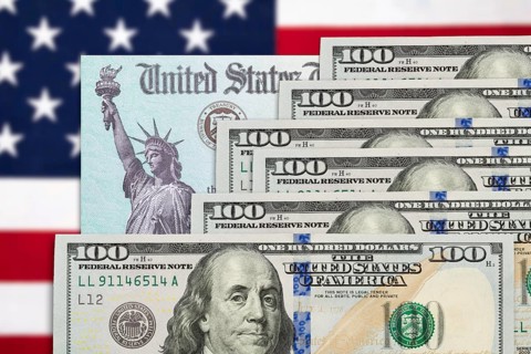 Six hundred dollars and United States IRS stimulus check resting on american flag