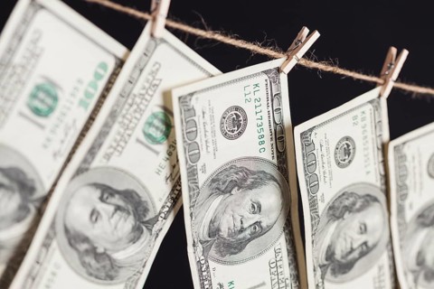Hundred dollar bills hanging from a clothesline on a dark background