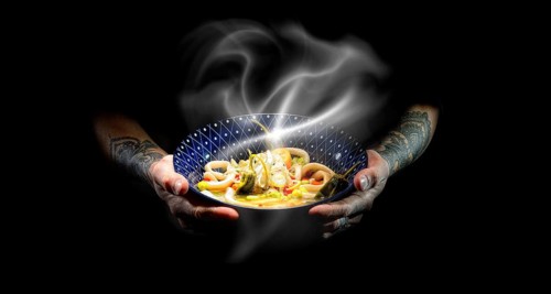 Tattooed hands hold plate with udon bowl