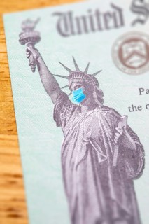 United states IRS stimulus check with statue of liberty wearing medical face mask