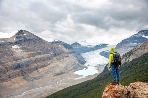 Hiker standing on rocks overlooking valley with glacier tongue