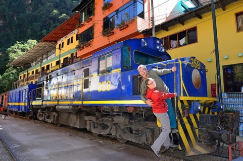 Two tourists at the locomotive of the Perurail in the station