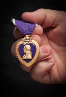 Male hand holding the United States armed forces purple heart medal