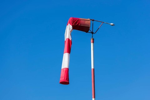 Red and white windsock against blue sky
