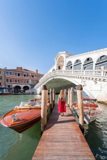Young woman with red dress at a pier with boats
