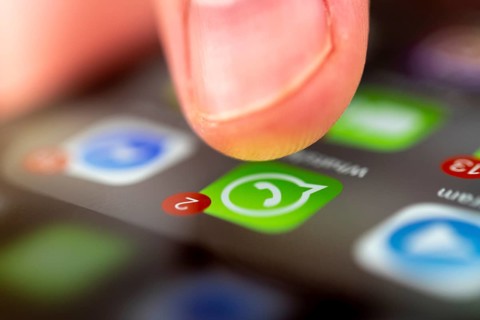 Finger tapping on screen with app icons of messenger services and social networks