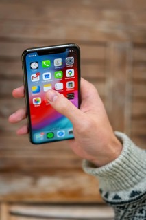 Hand haelt iPhone 11 Pro mit Homescreen