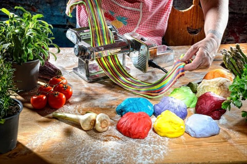Cook with pasta machine making coloured pasta dough