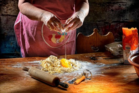 Woman beats egg on flour for pasta dough