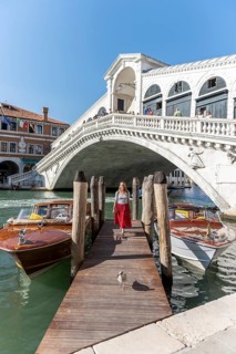 Young woman with red dress at a pier with boats
