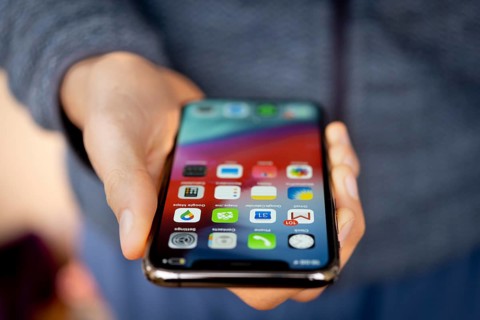 Hand haelt iPhone 11 Pro mit Homescreen