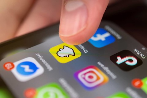 Finger tapping on screen with app icons of messenger services and social networks
