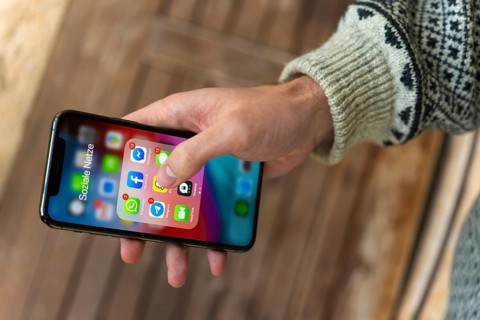Hand haelt iPhone 11 Pro mit App-Icons von Messenger Diensten und Sozialen Netzwerken
