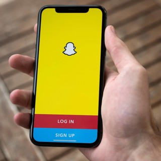 Hand haelt iPhone 11 Pro mit geoeffneter Snapchat App