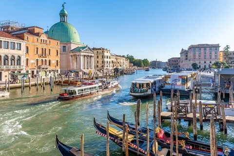 Gondolas and boats on the Grand Canal with church San Simeone Piccolo at the Ponte degli Scalzi