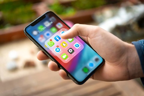 Hand haelt iPhone 11 Pro mit App-Icons von Messenger Diensten und Sozialen Netzwerken